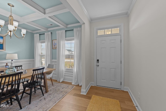 foyer with a notable chandelier, crown molding, light wood finished floors, visible vents, and coffered ceiling