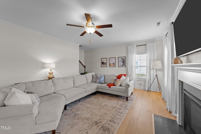 living area featuring ornamental molding, stairway, a fireplace with flush hearth, and light wood-style flooring