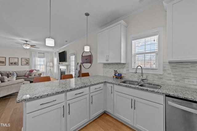 kitchen featuring light wood-style floors, dishwasher, a peninsula, and a sink