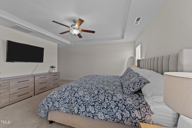 bedroom with a tray ceiling, visible vents, and carpet