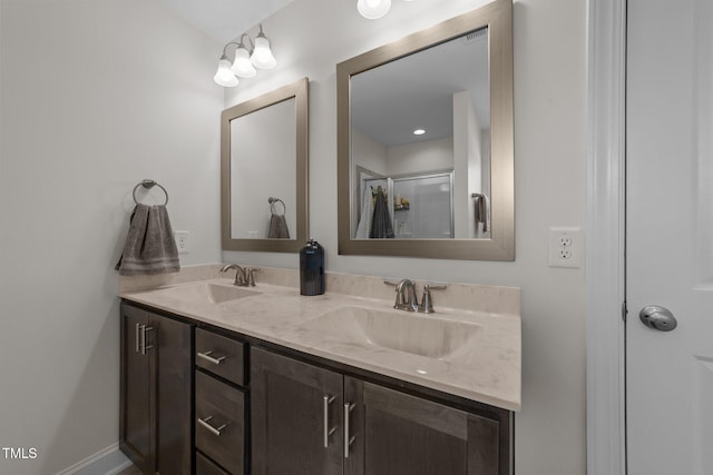 bathroom featuring double vanity, baseboards, an enclosed shower, and a sink