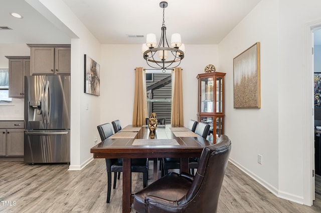 dining space with visible vents, baseboards, light wood-type flooring, and a chandelier