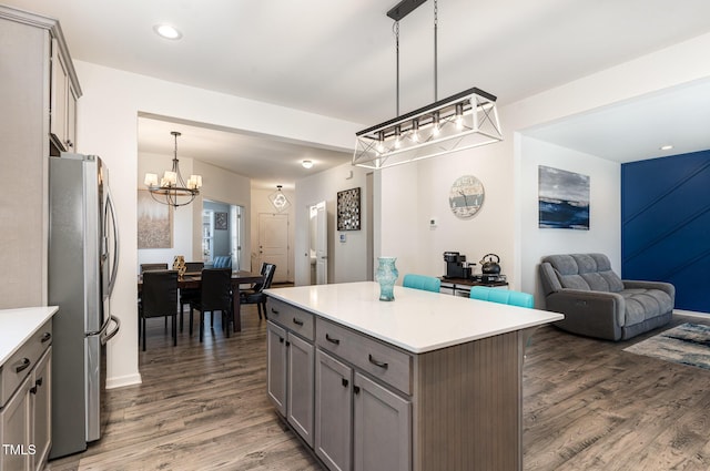 kitchen featuring gray cabinets, freestanding refrigerator, dark wood-type flooring, light countertops, and a chandelier