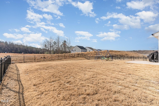 view of yard featuring a rural view, a playground, and a fenced backyard