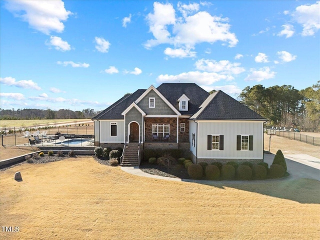 view of front of home with board and batten siding, fence, and a fenced in pool