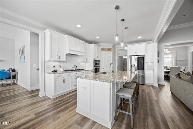 kitchen featuring premium range hood, wood finished floors, a sink, appliances with stainless steel finishes, and crown molding