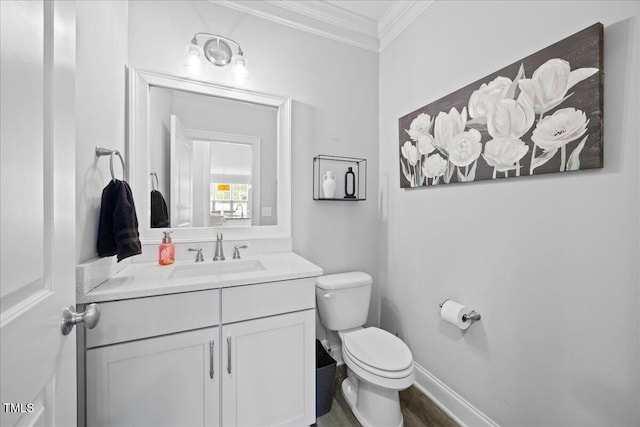 half bathroom featuring toilet, baseboards, crown molding, and vanity