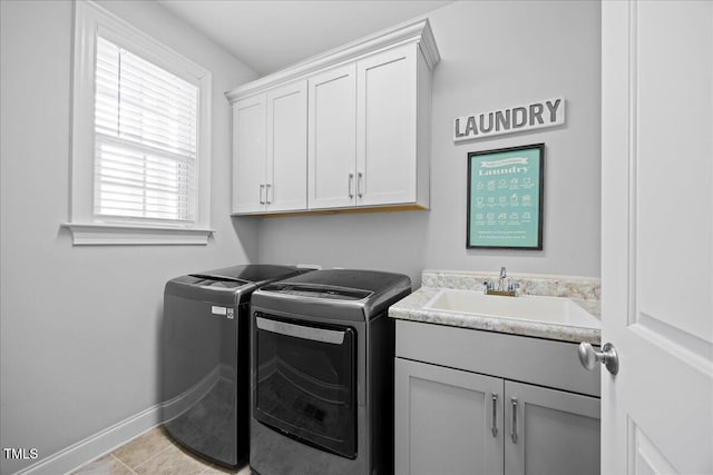 laundry area with a sink, washing machine and clothes dryer, cabinet space, and baseboards