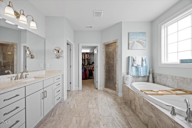 bathroom with visible vents, a spacious closet, a stall shower, vanity, and a bath