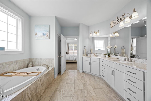 ensuite bathroom featuring double vanity, a garden tub, ensuite bath, and a sink