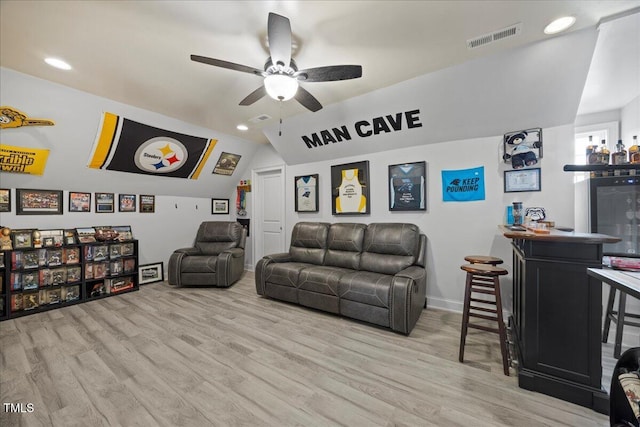 living area with lofted ceiling, a dry bar, wood finished floors, and visible vents