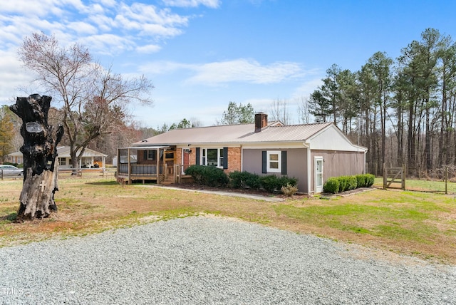 single story home featuring metal roof, a front lawn, a chimney, and brick siding