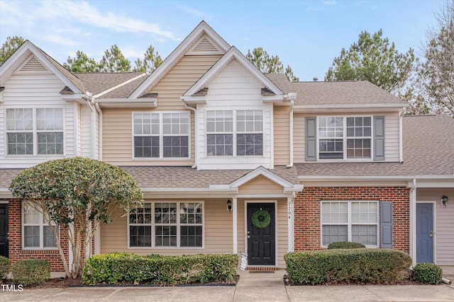 townhome / multi-family property with brick siding and roof with shingles