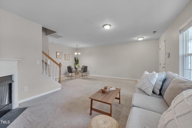 living room with visible vents, baseboards, a fireplace with flush hearth, stairway, and carpet floors