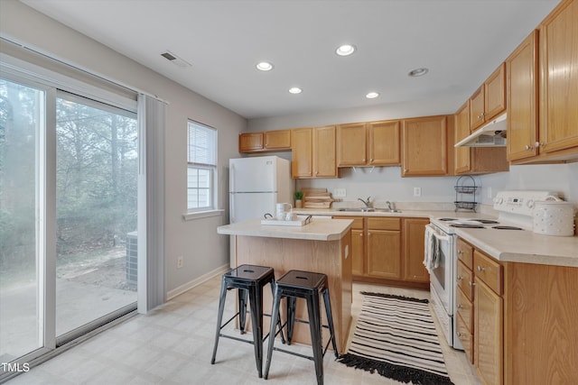 kitchen with under cabinet range hood, white appliances, a sink, visible vents, and light floors