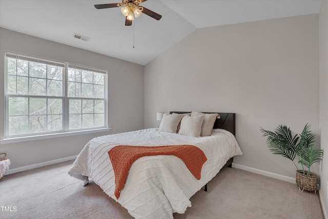 carpeted bedroom with baseboards, visible vents, vaulted ceiling, and a ceiling fan