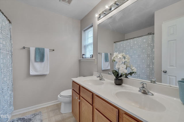 bathroom featuring baseboards, a sink, toilet, and double vanity