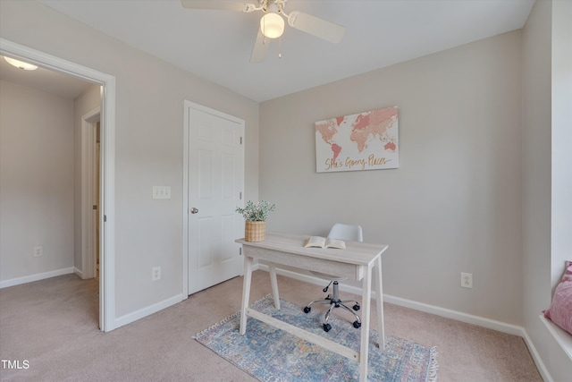 office featuring light carpet, baseboards, and a ceiling fan