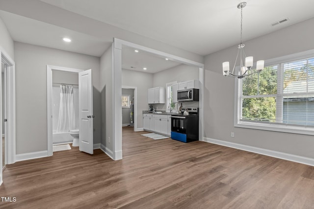 kitchen with white cabinetry, black / electric stove, stainless steel microwave, and wood finished floors