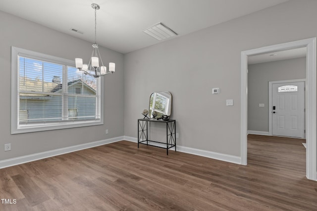 unfurnished dining area with dark wood-style floors, an inviting chandelier, visible vents, and baseboards