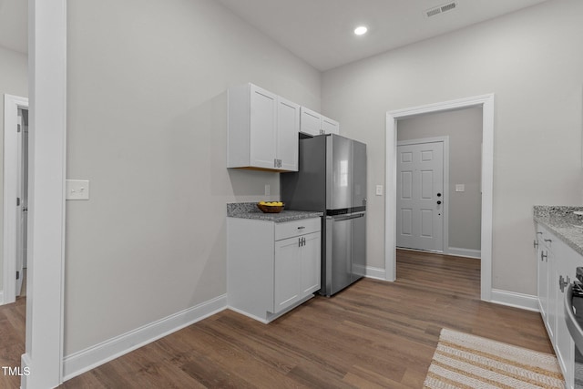 kitchen featuring freestanding refrigerator, visible vents, and wood finished floors