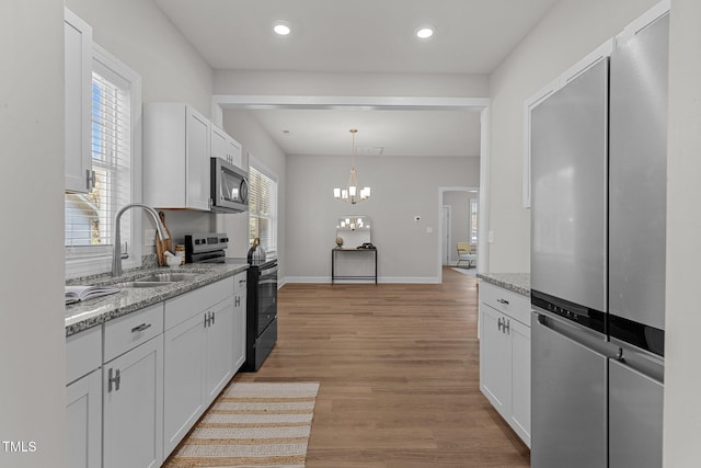 kitchen with range with electric stovetop, stainless steel microwave, light wood-style flooring, white cabinets, and a sink