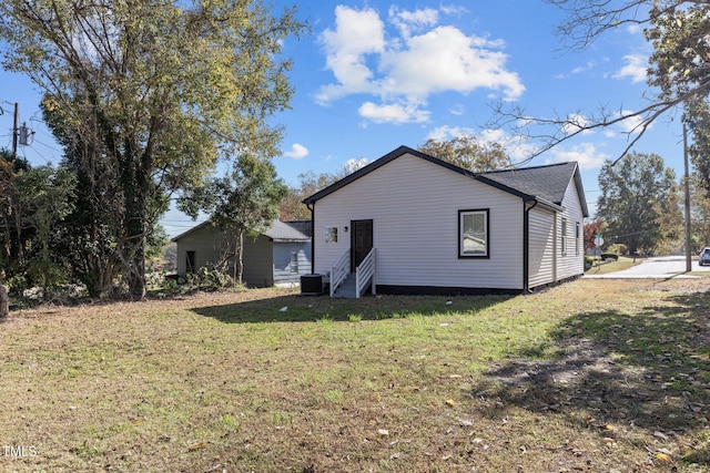 back of property with entry steps, central AC unit, and a yard