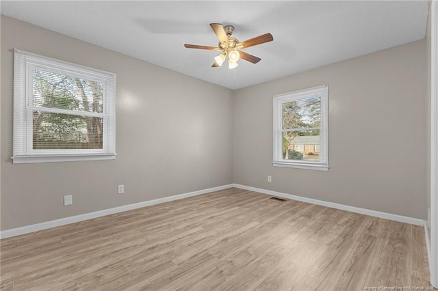 unfurnished room with a wealth of natural light, light wood-style flooring, and baseboards
