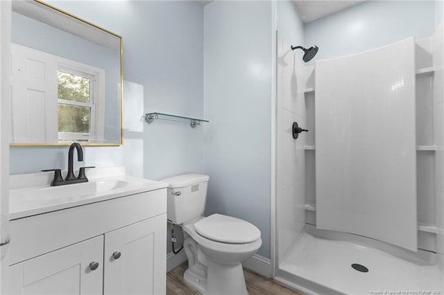 bathroom featuring toilet, wood finished floors, a shower stall, and vanity
