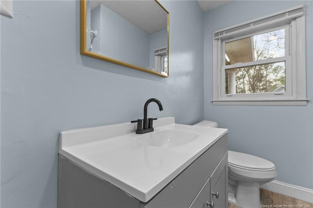 bathroom with baseboards, vanity, and toilet