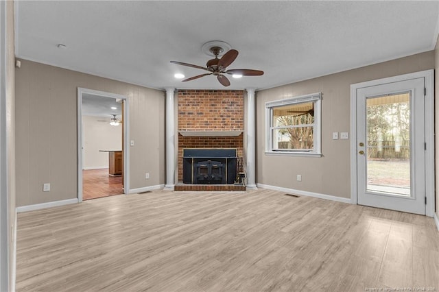 unfurnished living room with ceiling fan, a fireplace, visible vents, baseboards, and light wood-style floors