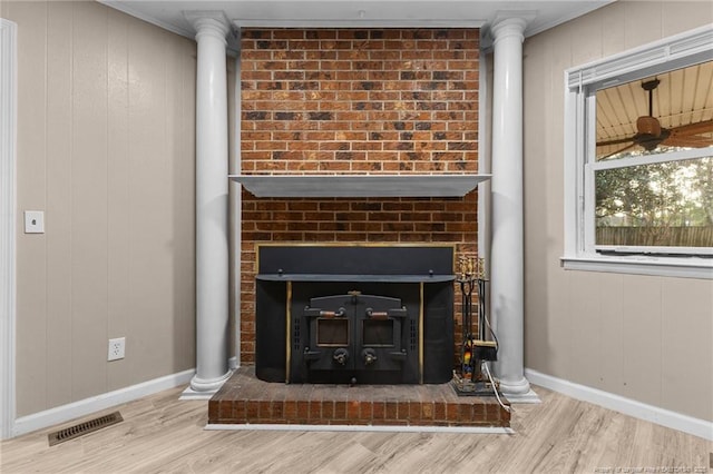 details featuring wood finished floors, visible vents, baseboards, a brick fireplace, and ornate columns