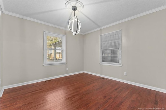 spare room featuring dark wood-style floors, a textured ceiling, baseboards, and crown molding