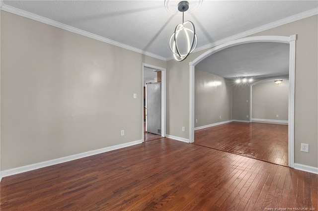 spare room featuring hardwood / wood-style flooring, baseboards, arched walkways, and ornamental molding