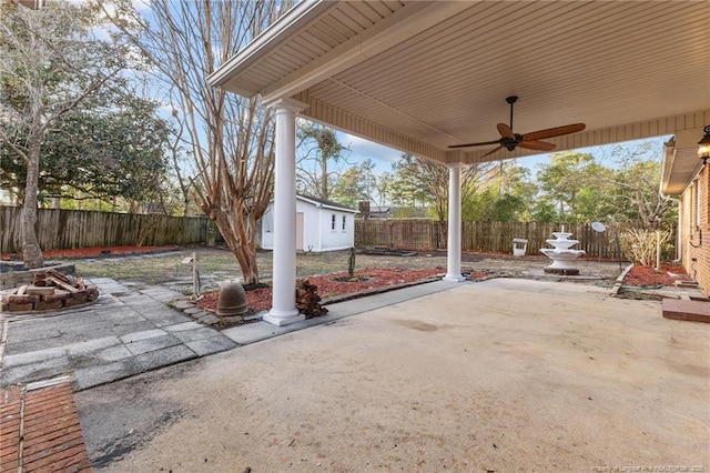 view of patio / terrace with an outdoor fire pit, a fenced backyard, ceiling fan, and an outdoor structure
