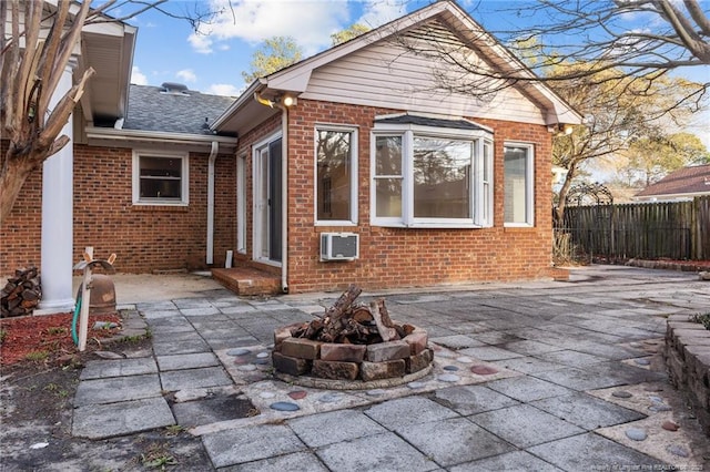 rear view of house featuring brick siding, fence, a fire pit, and a patio