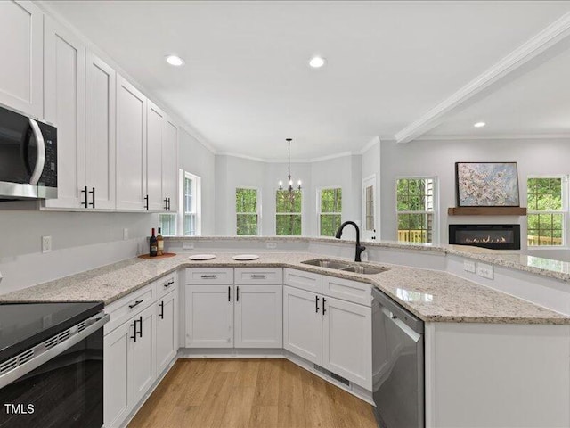 kitchen with a sink, a chandelier, crown molding, and stainless steel appliances