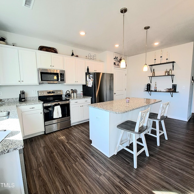 kitchen featuring a breakfast bar area, dark wood-type flooring, visible vents, appliances with stainless steel finishes, and a center island