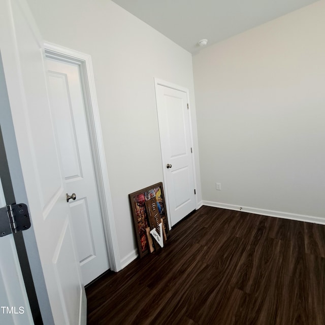 spare room featuring dark wood-style floors and baseboards