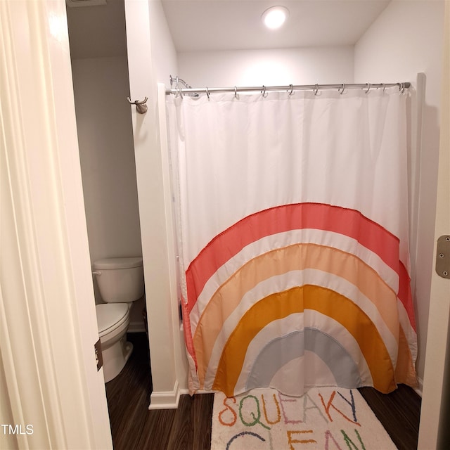 bathroom featuring a shower with shower curtain, wood finished floors, and toilet