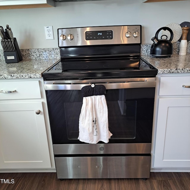 kitchen featuring dark wood-style floors, electric stove, white cabinetry, and light stone countertops