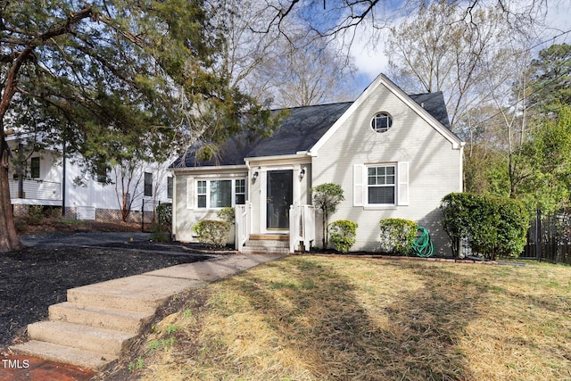 view of front facade featuring a front yard, brick siding, and fence