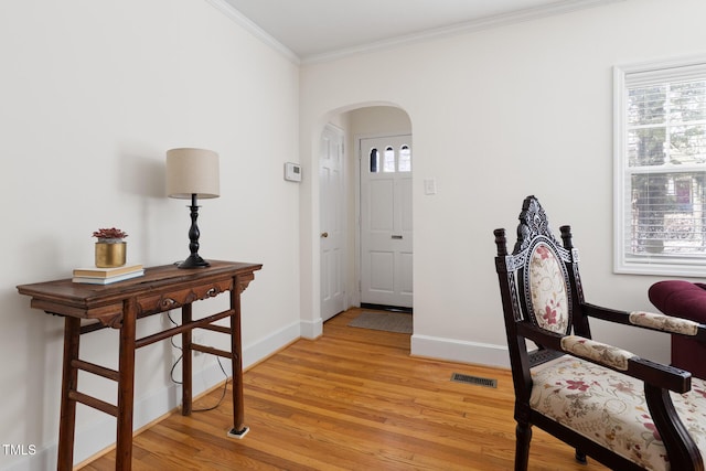 interior space featuring arched walkways, visible vents, baseboards, light wood-type flooring, and crown molding