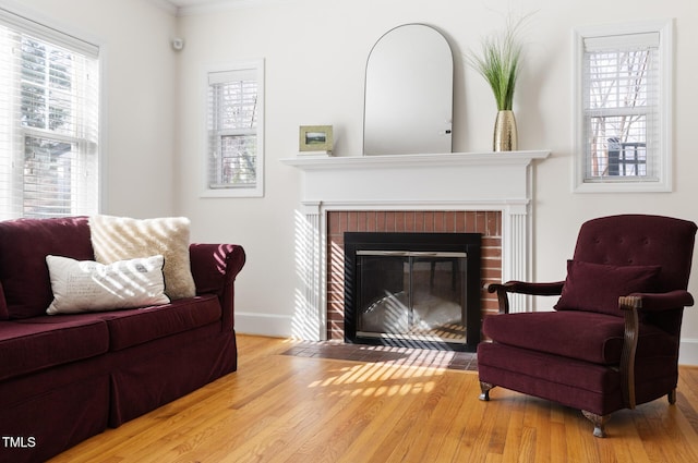 sitting room with a fireplace, plenty of natural light, and wood finished floors