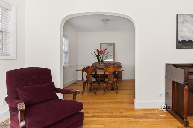 interior space with arched walkways, ornamental molding, baseboards, and light wood-style floors