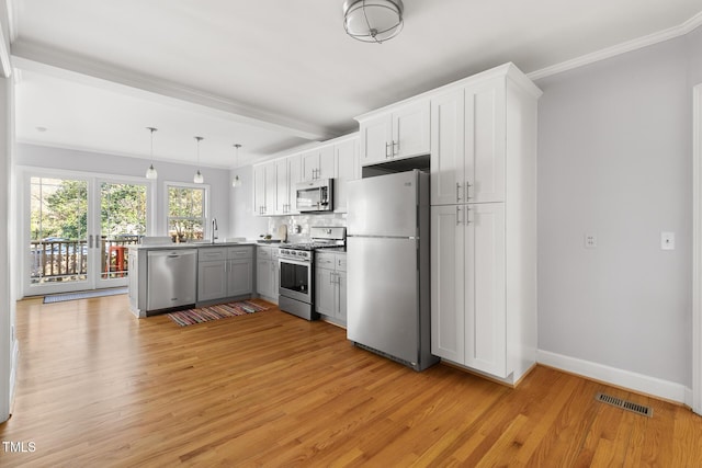 kitchen featuring visible vents, light wood-style flooring, appliances with stainless steel finishes, a sink, and a peninsula