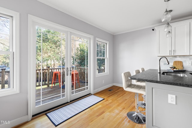 kitchen with light wood-style floors, white cabinetry, decorative backsplash, and a sink