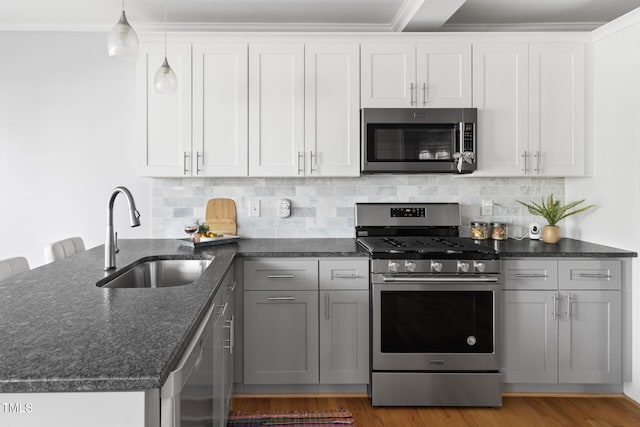 kitchen with wood finished floors, stainless steel appliances, tasteful backsplash, and a sink