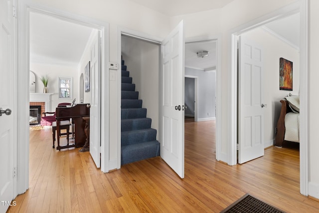 staircase with baseboards, wood-type flooring, a fireplace, and crown molding