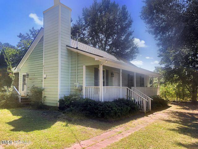 view of property exterior featuring a yard, covered porch, and a chimney